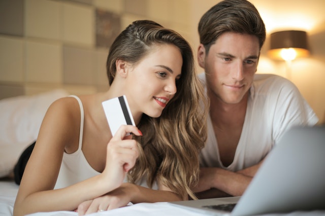 couple with credit card in front of laptop