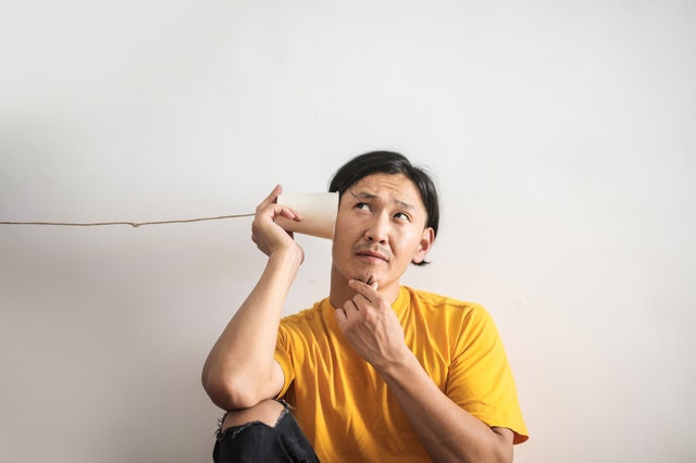 man holding one end of a cup used as phone