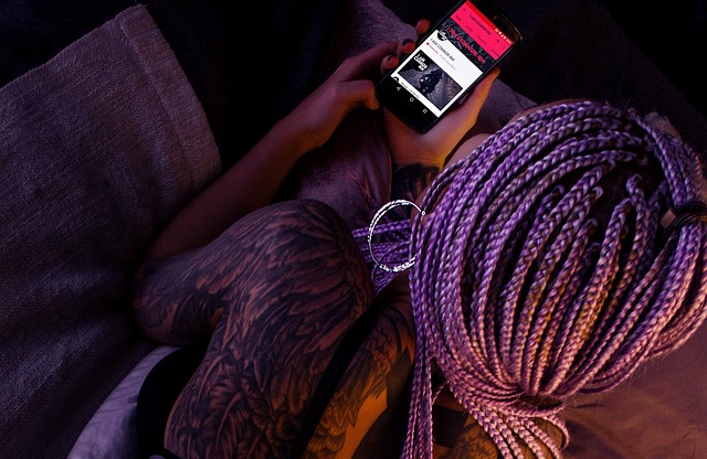 woman with braided purple hair and tattoos holding phone
